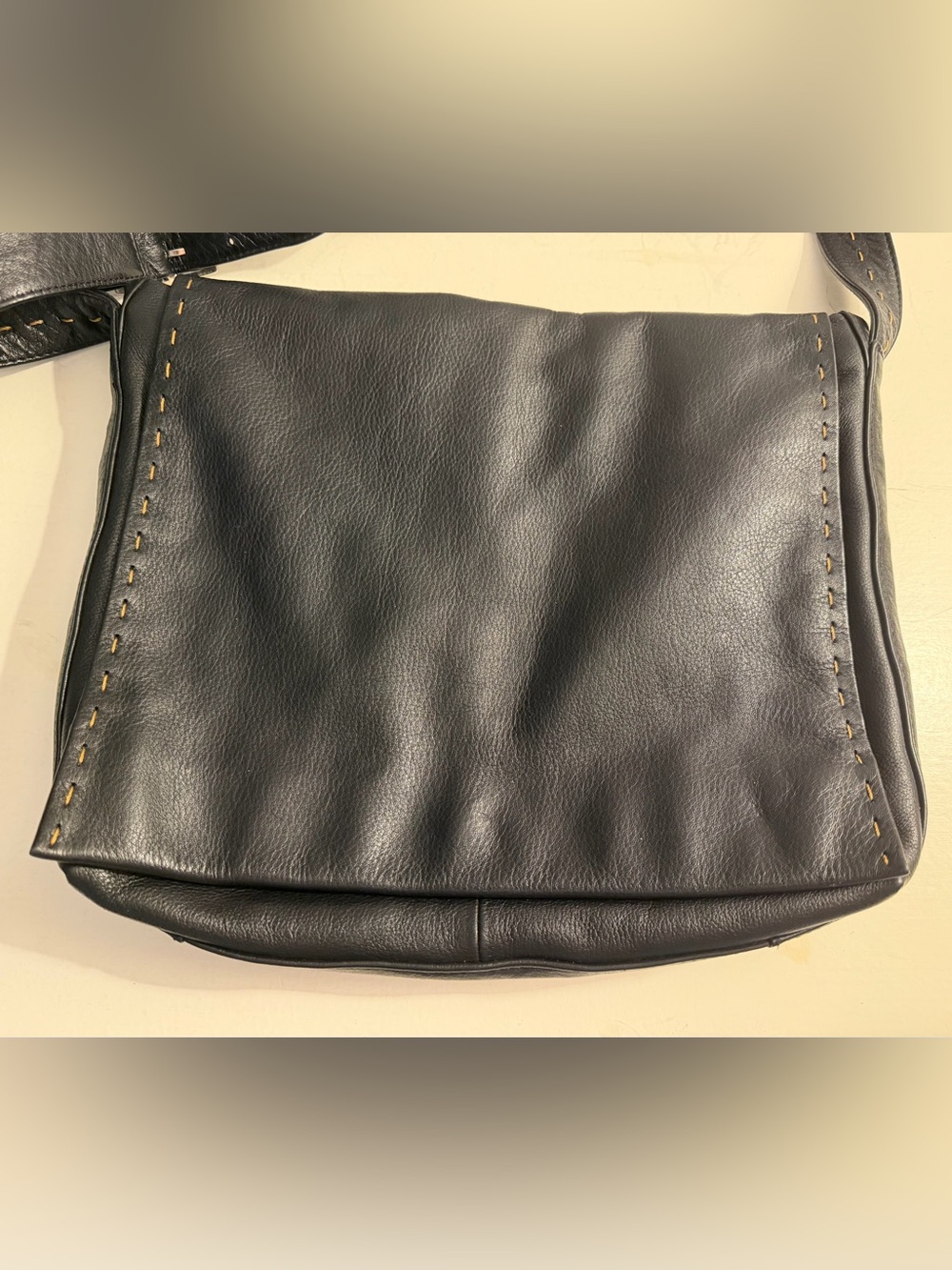 Denier Leather black leather messenger bag with whipstitching.